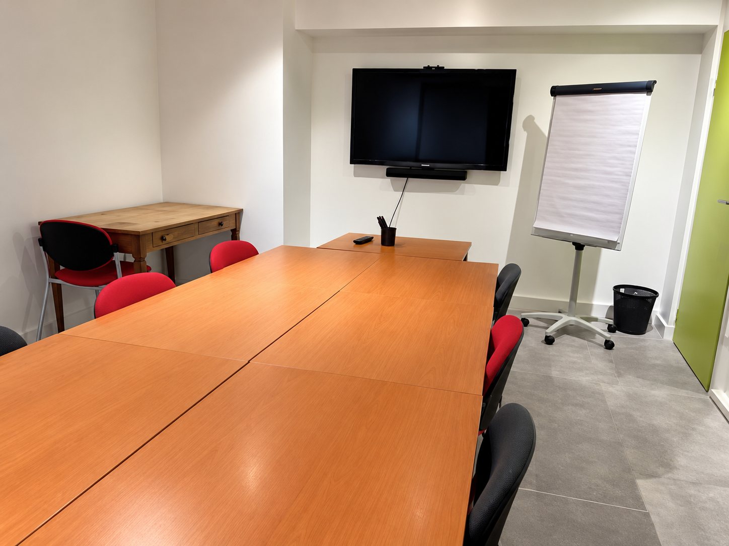 Salle de réunion avec grande table en bois et écran