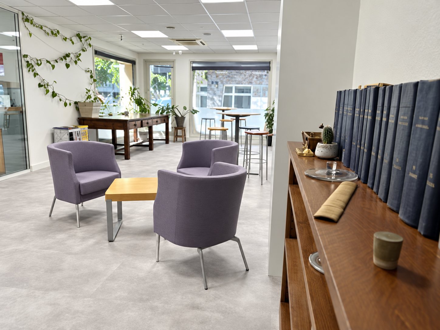 Salon d’accueil lumineux avec fauteuils violets et bibliothèque